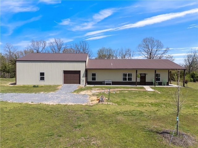 view of front of home with a garage, metal roof, driveway, and a front lawn