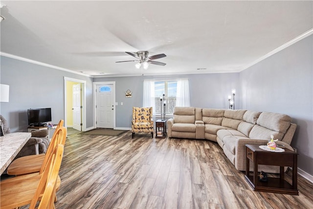 living room with wood finished floors, ceiling fan, baseboards, and ornamental molding