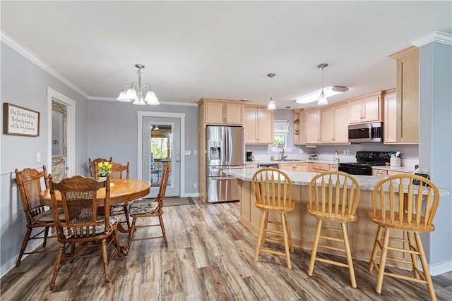 kitchen with baseboards, a sink, a chandelier, light wood-style floors, and stainless steel appliances