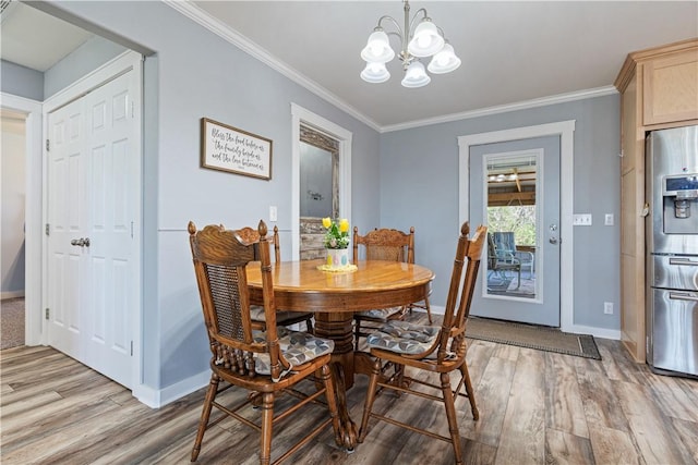 dining area featuring a chandelier, light wood-style floors, crown molding, and baseboards