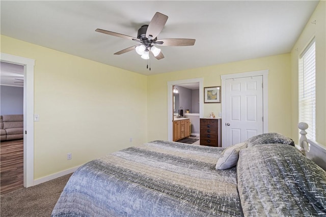 bedroom featuring carpet, ensuite bathroom, baseboards, and a ceiling fan