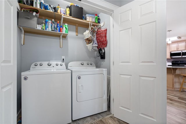 laundry area with independent washer and dryer, light wood-style floors, and laundry area
