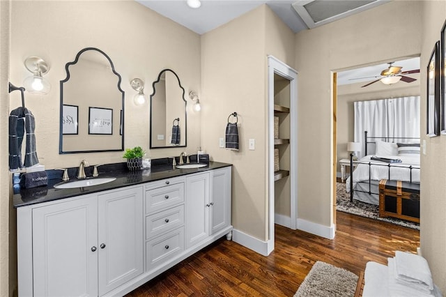 full bathroom featuring wood finished floors, double vanity, a sink, and baseboards