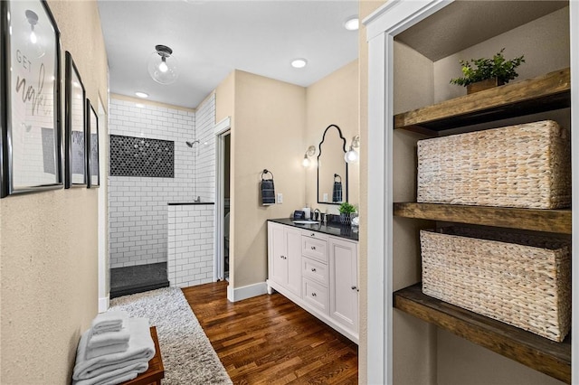 full bath featuring vanity, walk in shower, and wood finished floors