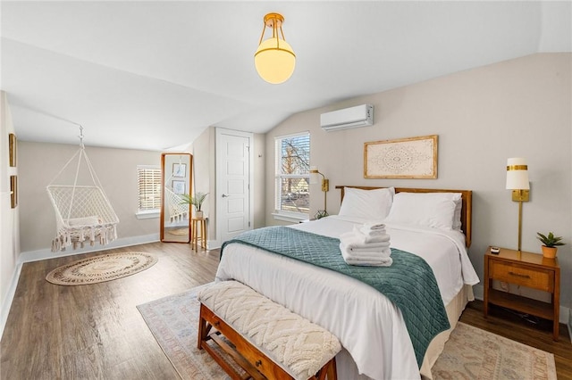 bedroom with baseboards, wood finished floors, vaulted ceiling, and a wall unit AC
