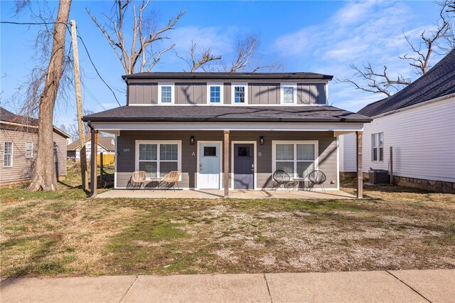bungalow-style house featuring board and batten siding, central air condition unit, covered porch, a patio area, and a front lawn