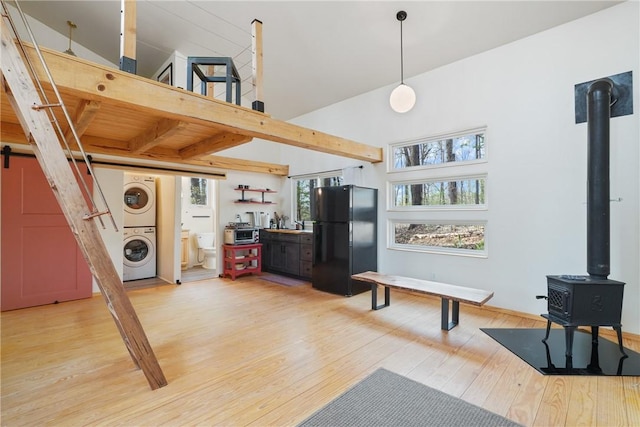 living area featuring a wood stove, light wood finished floors, and stacked washing maching and dryer