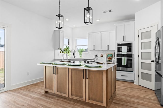 1900 Yellowstone Dr, Barling, AR 72923 - kitchen with tasteful backsplash, light wood-type flooring, a center island, appliances with stainless steel finishes, and light countertops