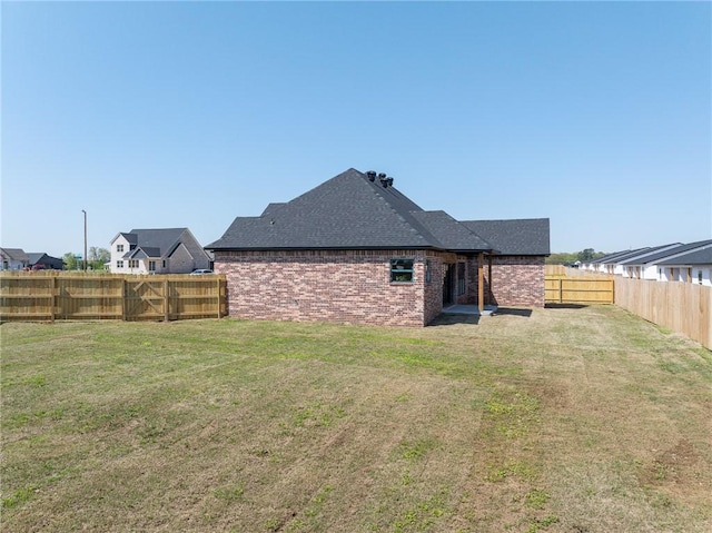 1900 Yellowstone Dr, Barling, AR 72923 - rear view of house with roof with shingles, brick siding, a fenced backyard, and a lawn
