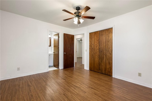 unfurnished bedroom featuring ensuite bath, baseboards, and wood finished floors