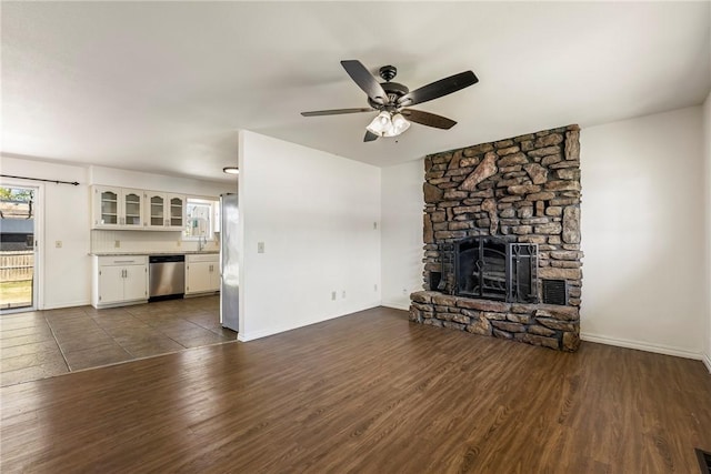 unfurnished living room with ceiling fan, a fireplace, dark wood finished floors, and baseboards