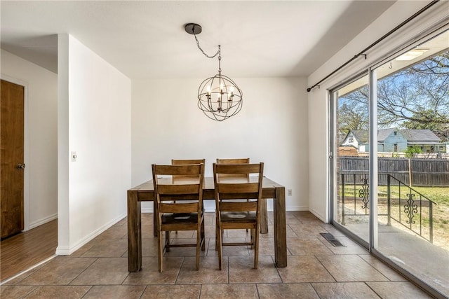 dining area featuring visible vents, a notable chandelier, and baseboards
