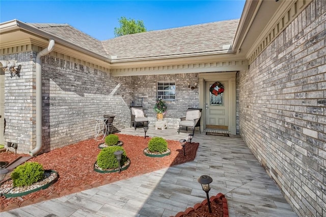 property entrance featuring a shingled roof and brick siding