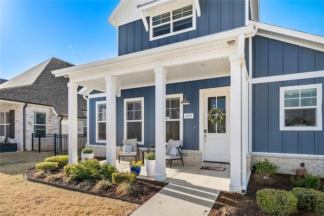 property entrance with covered porch, board and batten siding, and fence
