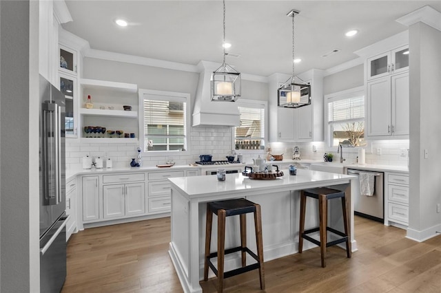 kitchen with stainless steel appliances, backsplash, a center island, white cabinets, and a breakfast bar area
