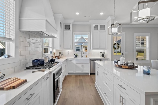 kitchen with custom exhaust hood, a sink, appliances with stainless steel finishes, light countertops, and recessed lighting
