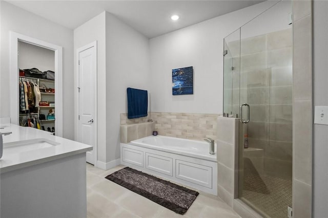 bathroom with a stall shower, a bath, a spacious closet, recessed lighting, and vanity