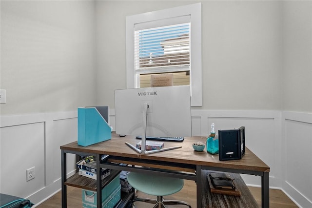 office featuring wood finished floors, wainscoting, and a decorative wall