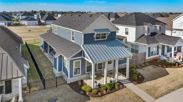 view of front of home featuring board and batten siding, a residential view, a fenced backyard, and metal roof