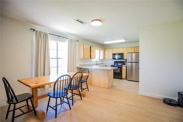 kitchen with light brown cabinets, a peninsula, black appliances, visible vents, and a sink