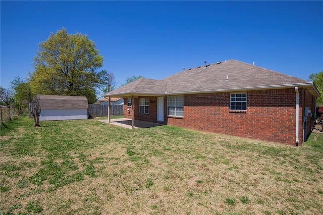back of property featuring an outdoor structure, a lawn, a patio area, a storage unit, and fence
