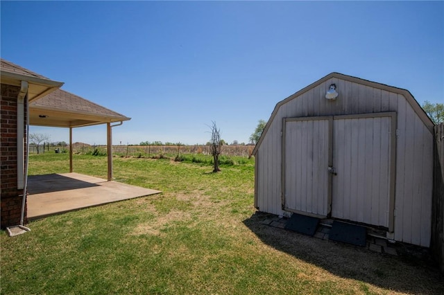 view of yard with a shed, a patio, fence, and an outbuilding