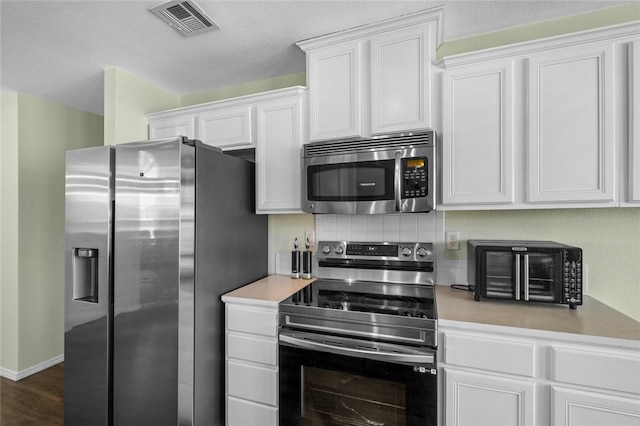 1901 SW Columbus Rd, Bentonville, AR 72713 - kitchen with stainless steel appliances, light countertops, white cabinets, and dark wood-style flooring
