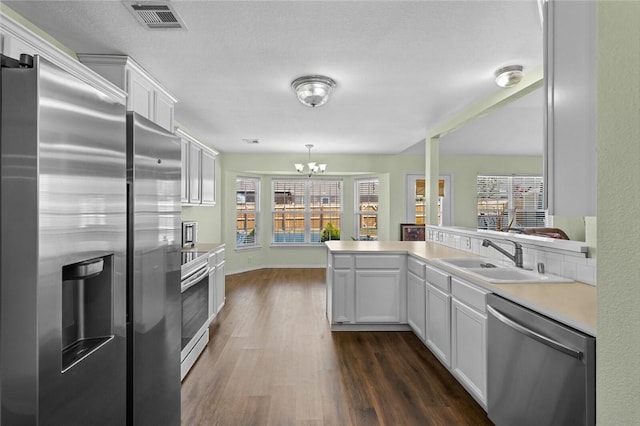1901 SW Columbus Rd, Bentonville, AR 72713 - kitchen with stainless steel appliances, a sink, a chandelier, dark wood-type flooring, and light countertops