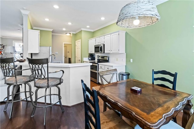 dining room featuring dark wood-type flooring, crown molding, and recessed lighting