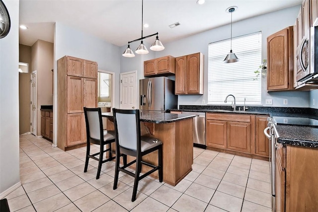 kitchen with light tile patterned flooring, a sink, appliances with stainless steel finishes, and plenty of natural light