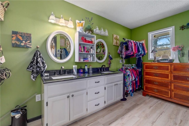 30 Strichen Dr, Bella Vista, AR 72715 - bathroom with double vanity, a textured ceiling, a sink, and wood finished floors