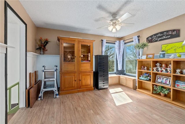 30 Strichen Dr, Bella Vista, AR 72715 - interior space featuring light wood finished floors, a textured ceiling, a ceiling fan, and a wainscoted wall
