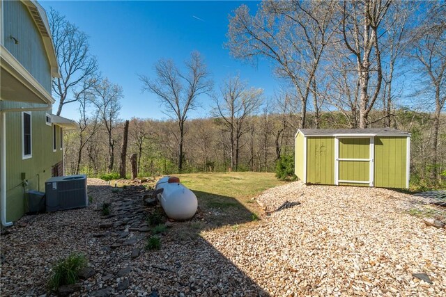 30 Strichen Dr, Bella Vista, AR 72715 - view of yard featuring central AC unit, a storage shed, a view of trees, and an outbuilding