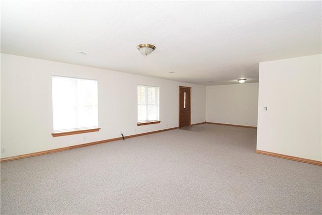 unfurnished room with baseboards and light carpet