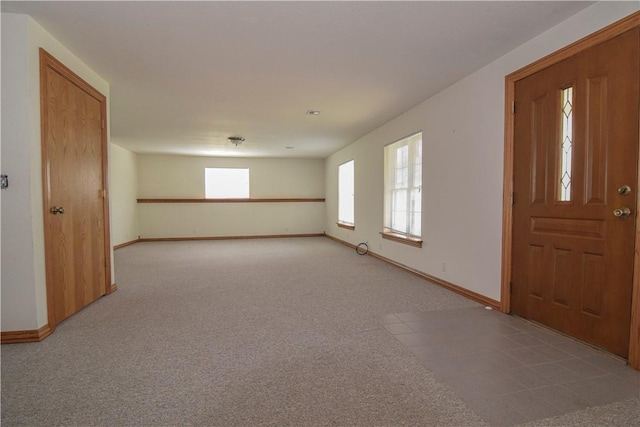foyer entrance featuring baseboards and light carpet