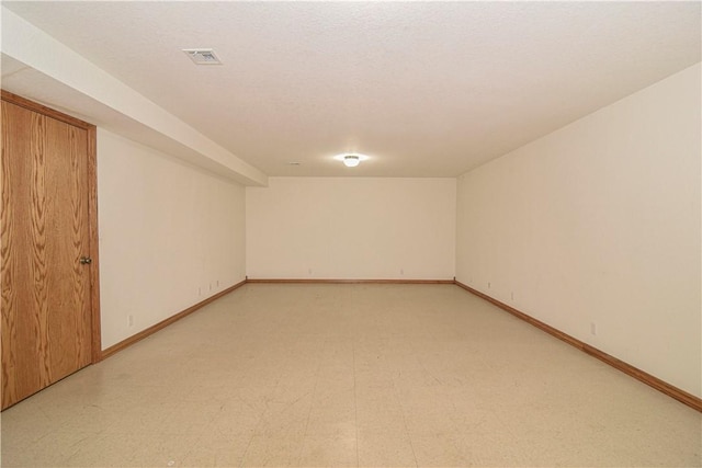 finished basement featuring visible vents, baseboards, and light floors