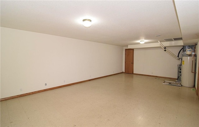 finished basement featuring baseboards, water heater, and light floors