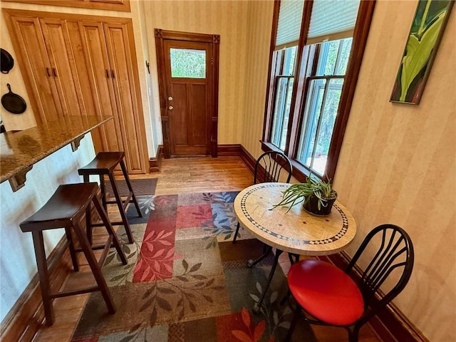 interior space with wallpapered walls, wood finished floors, and baseboards