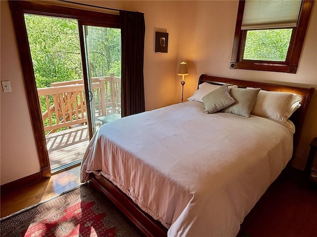 bedroom featuring wood finished floors, access to outside, and baseboards
