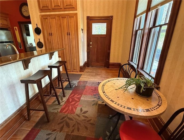 interior space featuring wallpapered walls, plenty of natural light, dark wood-type flooring, and baseboards