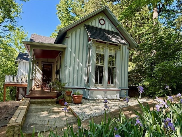 exterior space with board and batten siding, roof with shingles, and a wooden deck
