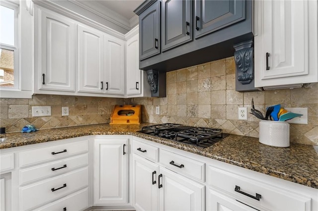 kitchen with white cabinets, backsplash, ornamental molding, dark stone counters, and black gas stovetop