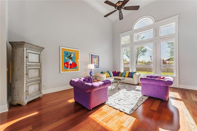 living room with high vaulted ceiling, a ceiling fan, wood finished floors, baseboards, and ornamental molding