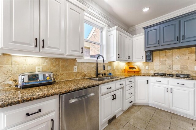 kitchen featuring dishwasher, dark stone countertops, a sink, and light tile patterned floors