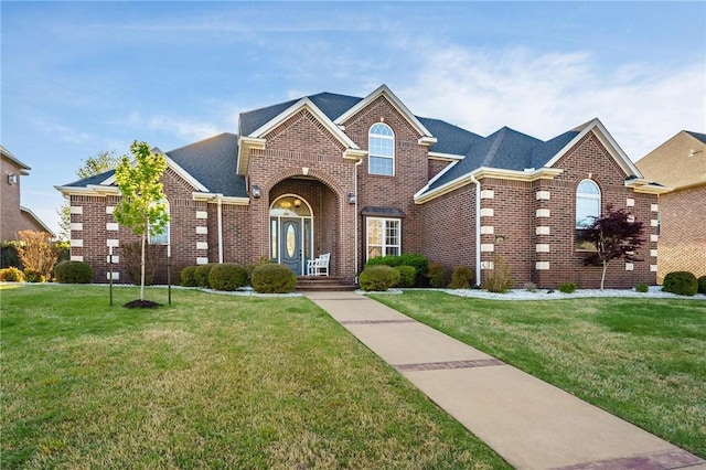 traditional home featuring a front lawn, brick siding, and roof with shingles