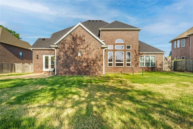 rear view of property with brick siding, a yard, a patio, and fence