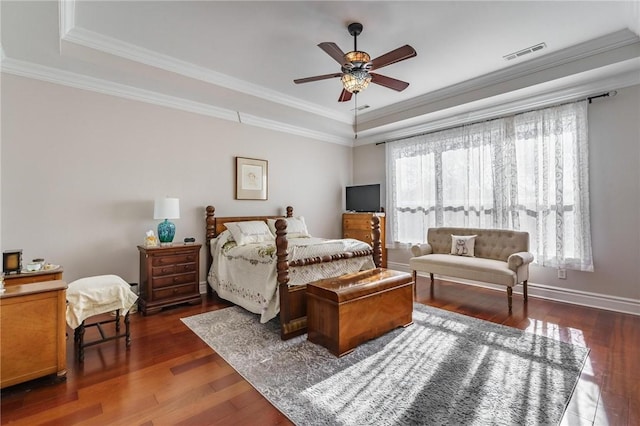 bedroom featuring crown molding, wood finished floors, visible vents, and a raised ceiling
