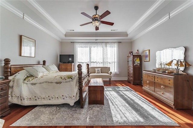 bedroom featuring a raised ceiling, wood finished floors, visible vents, ornamental molding, and ceiling fan
