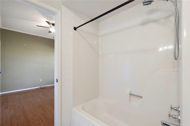 bathroom featuring shower / tub combination, wood finished floors, baseboards, and ceiling fan