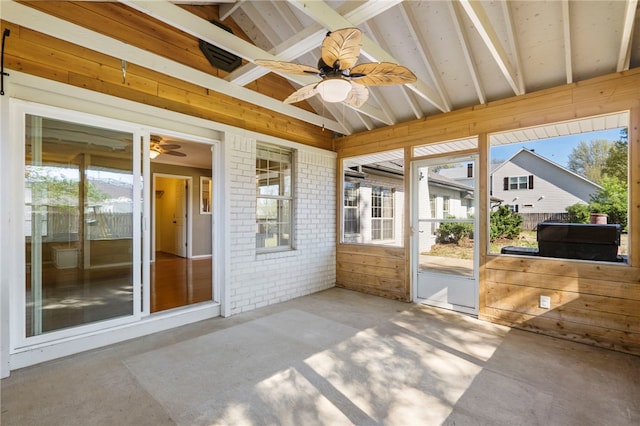 unfurnished sunroom with beamed ceiling and a ceiling fan